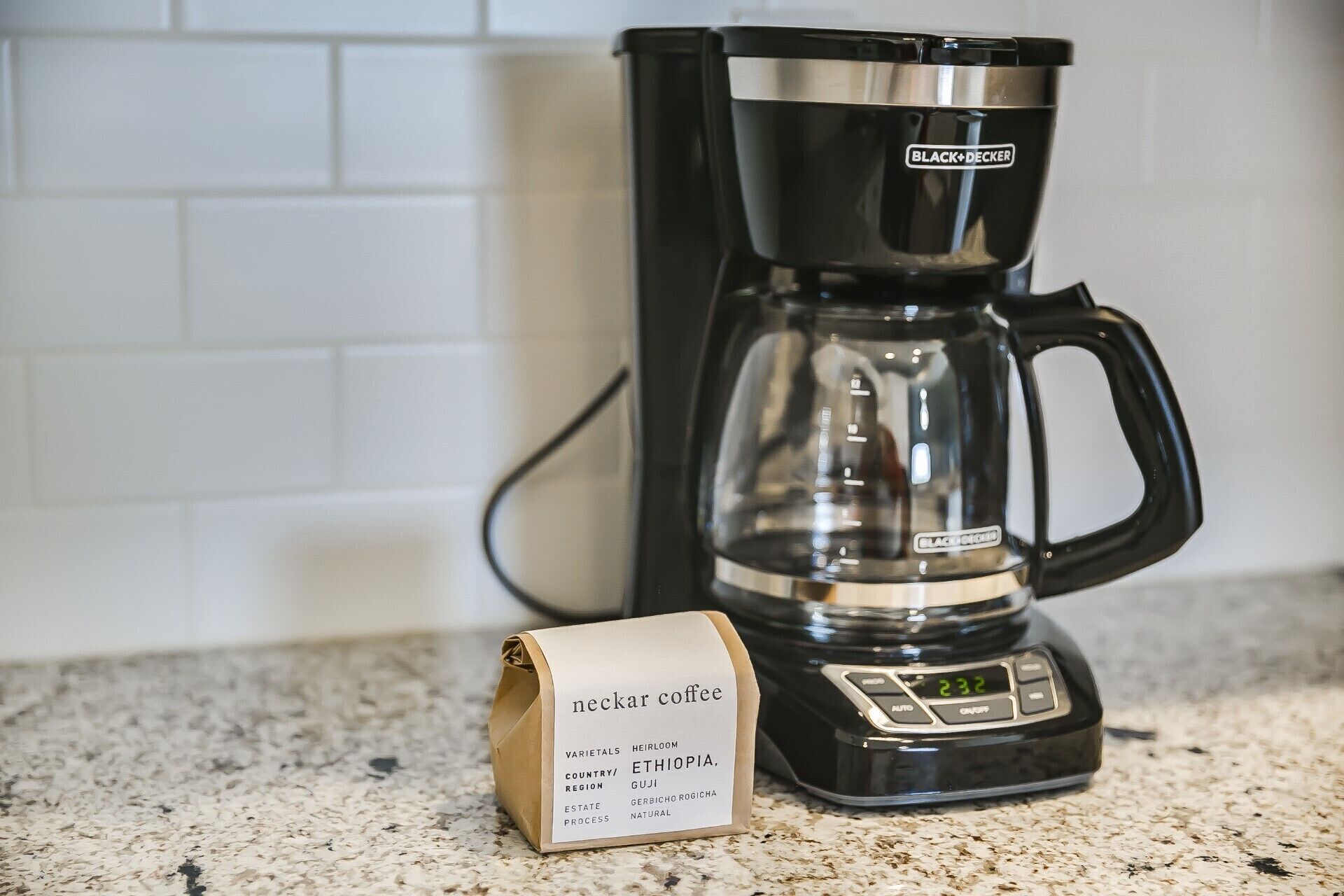 A black coffee maker with a digital display on a kitchen counter.
