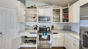 Una cocina con gabinetes blancos, estufa de acero inoxidable y microondas.