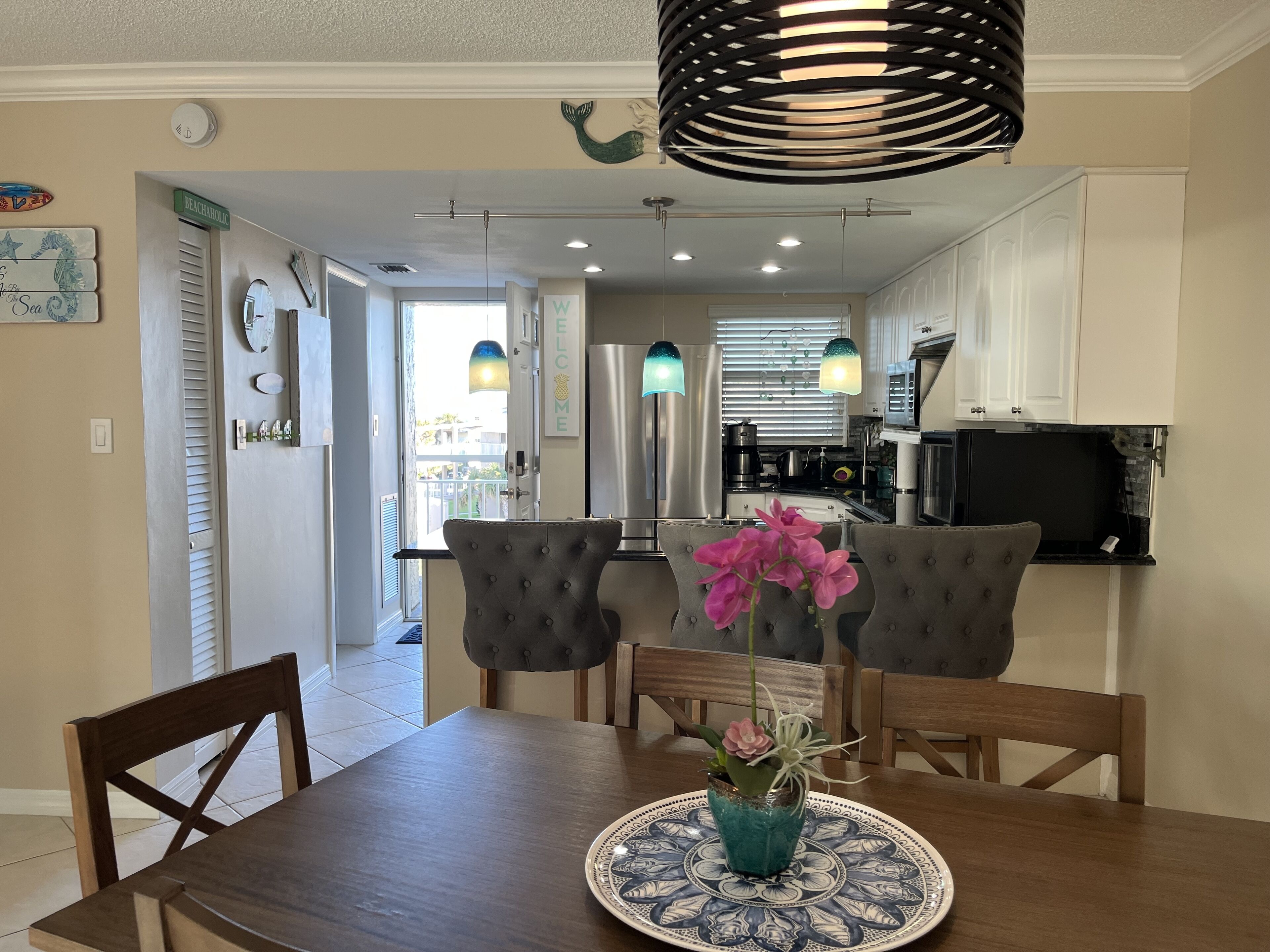 Un coin repas comprenant une table en bois, quatre chaises, un vase avec des fleurs et une assiette décorative.