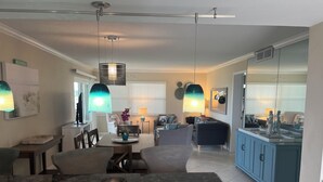 Et moderne køkken med en central ø, et spiseområde med bord og stole, samt en stue med sofa og sofabord.