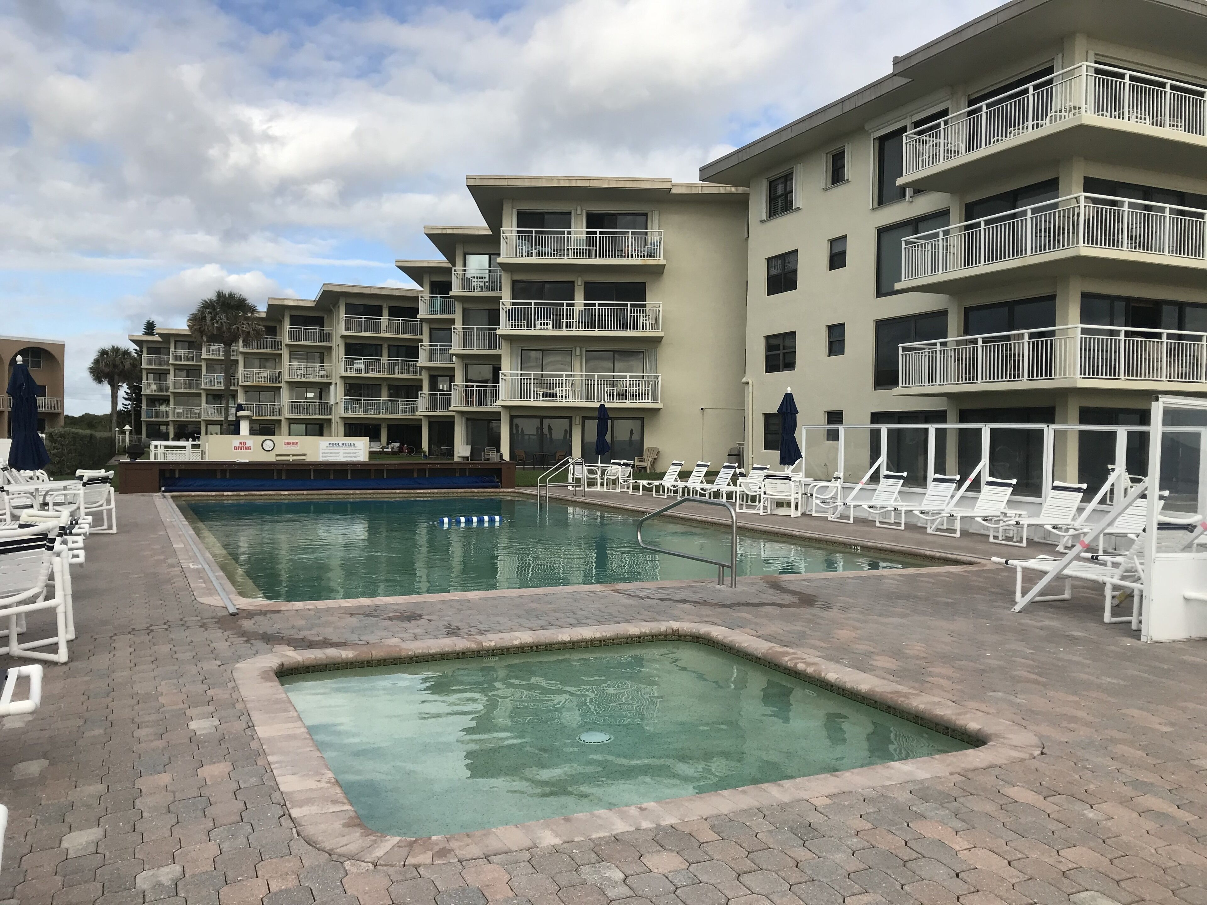 A swimming pool area with lounge chairs and a sign indicating no diving.