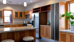 Een moderne keuken met houten kasten, roestvrijstalen apparatuur en een centraal kookeiland met krukken.