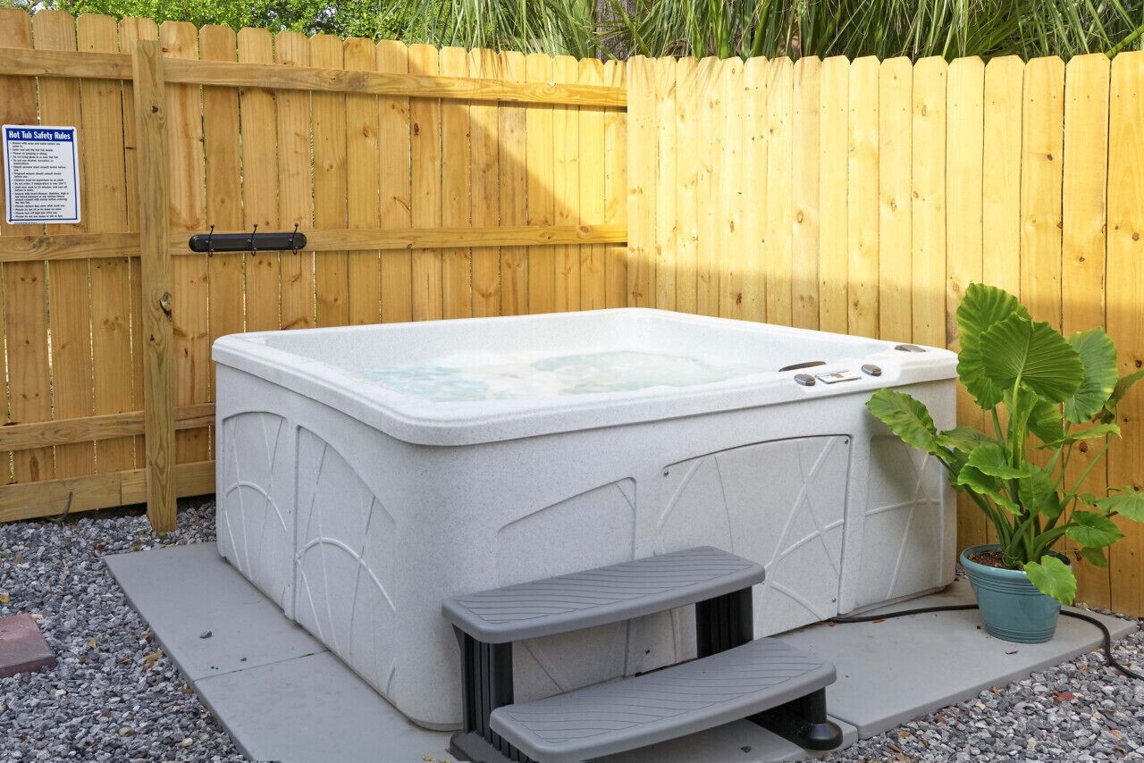 Ein Whirlpool mit Stufen und einem hölzernen Zaun im Hintergrund.