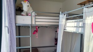 Habitación con literas, un juguete colgante, una lámpara y un cojín estampado.