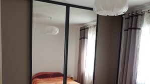 Un dormitorio con cama, armario y luz en el techo.