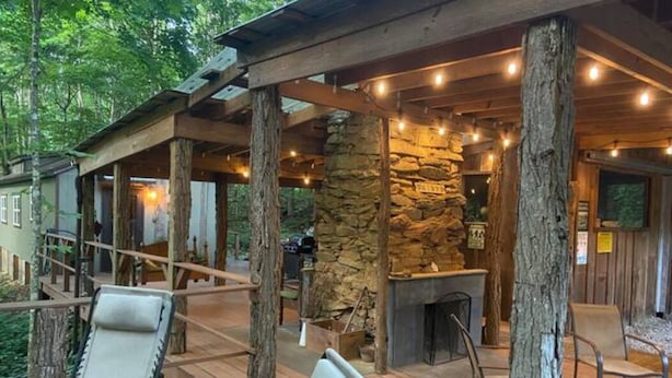A wooden deck with outdoor seating, a stone fireplace, and string lights. - Hideaway from it all ! Holyfield Hideaway, Flag Pond, Tennessee  (Flag Pond)
