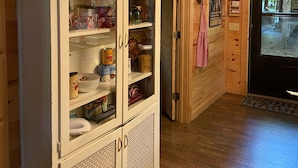 A wooden interior with a cabinet containing kitchen items, a door with a red and white checkered towel, and a chandelier. - Hideaway from it all ! Holyfield Hideaway, Flag Pond, Tennessee  (Flag Pond)