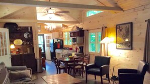 A cozy living room with a wooden ceiling, a dining area with a table and chairs, and a kitchen in the background. - Hideaway from it all ! Holyfield Hideaway, Flag Pond, Tennessee  (Flag Pond)