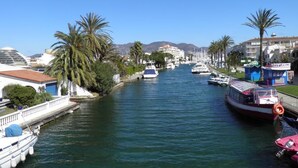 A canal with boats, palm trees, and buildings along the banks. - Modern 4-bedroom villa, private pool, near beach.  (Empuriabrava)