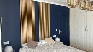 A bedroom with a bed, bedside table, lamp, wardrobe, and a wall with vertical wooden slats. - Modern 4-bedroom villa, private pool, near beach.  (Empuriabrava)