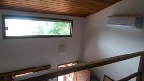 Huone, jossa on ikkuna, kattotuuletin ja portaikko.
