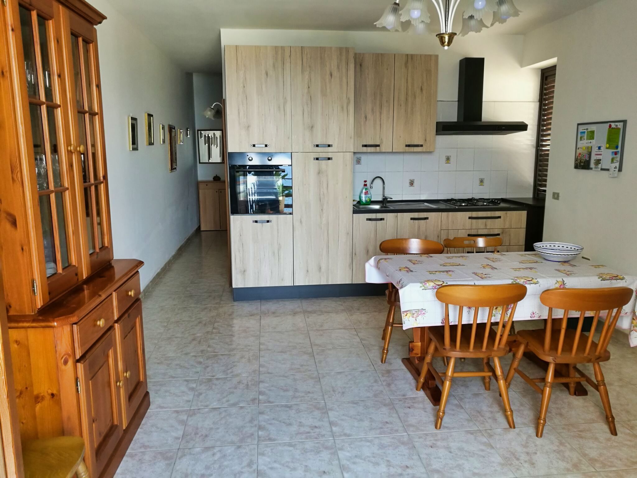 Una cucina moderna con mobili in legno, un tavolo da pranzo con sedie e un forno integrato.