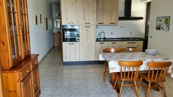 Una cucina moderna con mobili in legno, un tavolo da pranzo con sedie e un forno integrato.