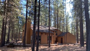 A cabin with a large deck and multiple rooms, surrounded by tall pine trees. - SM BBR home - Perfect for two families! (Sisters)