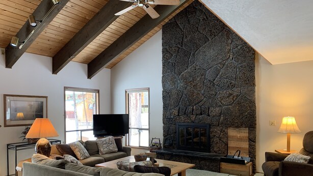 A cozy living room with a stone fireplace, wooden beams, and comfortable seating. - SM BBR home - Perfect for two families! (Sisters)