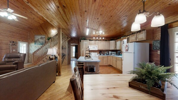 Cozy cabin-style interior with a central island breakfast bar, wooden ceiling, and large window.