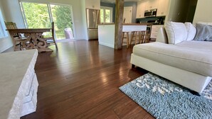 Un vaste espace de vie comprenant un grand canapé, un plancher en bois et une cuisine à l’arrière-plan.