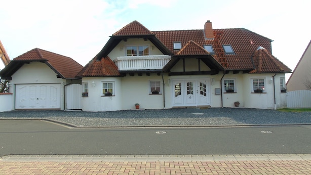 A two-story house with a traditional design, featuring a balcony on the upper floor, a garage on the left, and a well-maintained driveway. - Holiday apartment / accommodation for business travelers (Sandberg)