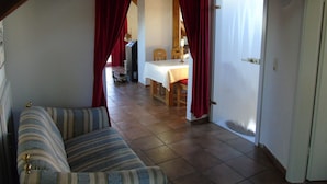 A room with a striped sofa, a dining area with a table and chairs, and a door leading to another room. - Holiday apartment / accommodation for business travelers (Sandberg)
