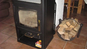 A wood-burning stove with a firebox, a door, and a log holder with firewood. - Holiday apartment / accommodation for business travelers (Sandberg)