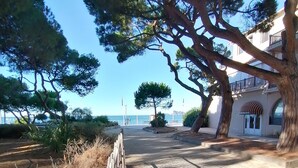 A coastal hotel with a paved walkway, a wooden fence, and a large tree. - A 200 m des Plages Appartement Avec Terrasse & Jardin (Saint-Cyr-sur-Mer)