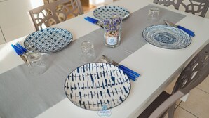 Una mesa de comedor adornada con platos estampados, servilletas azules y un florero de vidrio con flores.