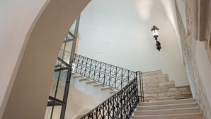 Una escalera con barandilla de hierro forjado que lleva a un rellano con una lámpara decorativa.