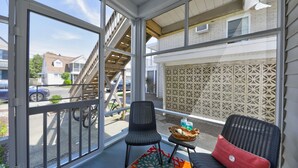 A balcony with wicker chairs, a small table with a basket, and a decorative pillow. - Steps to Rehoboth Beach and Boardwalk Dog Permitted (Rehoboth Beach)