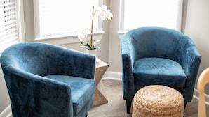 Two blue velvet armchairs, a woven ottoman, and a potted orchid by a window. - Steps to Rehoboth Beach and Boardwalk Dog Permitted (Rehoboth Beach)