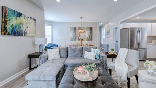A modern living room with a sectional sofa, a coffee table, and a dining area with a chandelier. - Steps to Rehoboth Beach and Boardwalk Dog Permitted (Rehoboth Beach)