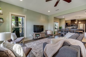 A modern living room with a flat-screen TV, comfortable seating, a dining area, and a kitchen. - The Wright Place: Your Perfect Beach Escape (Pensacola)