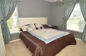 Relax in this serene bedroom with a large bed and natural light pouring in through the windows.