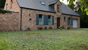 Et murhus med tegltag, garage og en velholdt græsplæne.