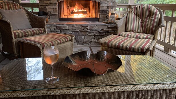 Una chimenea de piedra con una mesa de vidrio y sillones de mimbre.