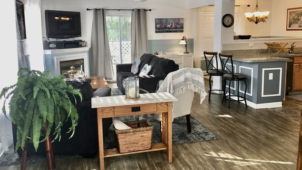 A modern living room with a fireplace, a television, a dining area, and a kitchen with a bar. - Rehoboth Beach-Luxury Villa-Linens Included (Rehoboth Beach)