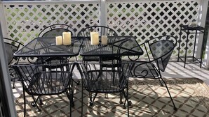 An outdoor patio with a white lattice fence, black metal tables and chairs, and candles on the tables. - Rehoboth Beach-Luxury Villa-Linens Included (Rehoboth Beach)