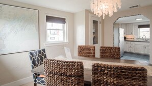 A dining area with a large map on the wall, wicker chairs, and a chandelier.