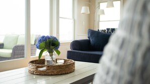 A wicker tray with a glass vase containing blue flowers on a white table.