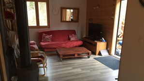Una sala de estar acogedora con un sofá rojo, una mesa de centro de madera y un televisor sobre un mueble de madera.