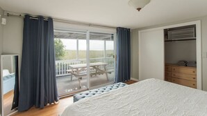A bedroom with a large bed, a sliding glass door to a balcony, a wardrobe, and a ceiling light.