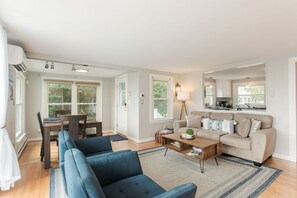 A spacious living room with a sofa, coffee table, and a dining area with chairs and a table.