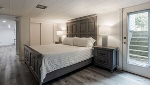 A bedroom with a large bed, bedside tables, and a door with a window.
