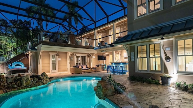 A two-story house with a swimming pool, outdoor seating, and a covered patio.