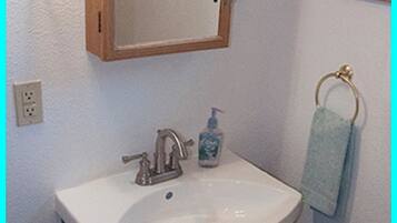 Un baño con un lavabo blanco, un mueble oscuro y un espejo encima.