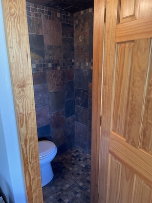 Experience a cozy bathroom retreat with a shower, toilet, and patterned tile floor.
