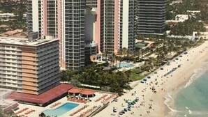 Um hotel à beira-mar com vários edifícios altos, uma praia e área de piscina.