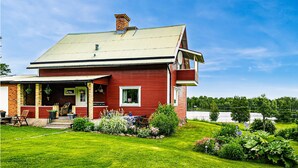 Una casa rossa con veranda, antenna parabolica e vista sul lago.