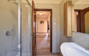Een badkamer met een douche, wastafel en spiegel.