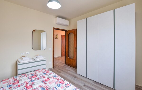 Un dormitorio con cama, armario, espejo y puerta que da a otra habitación.