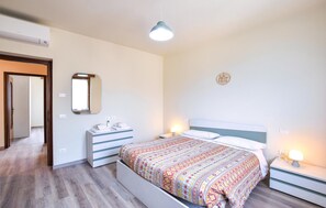 Een slaapkamer met een bed, nachtkastjes, een spiegel en een wandlamp.